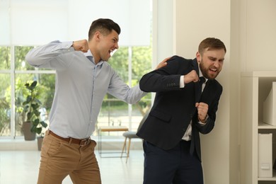 Photo of Emotional colleagues fighting in office. Workplace conflict