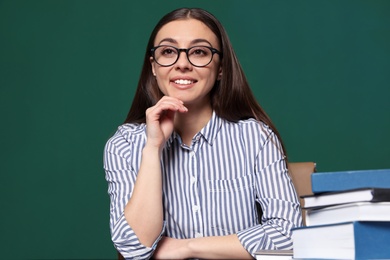 Photo of Portrait of young teacher at table against green background