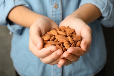 Woman holding organic almond nuts in hands, closeup