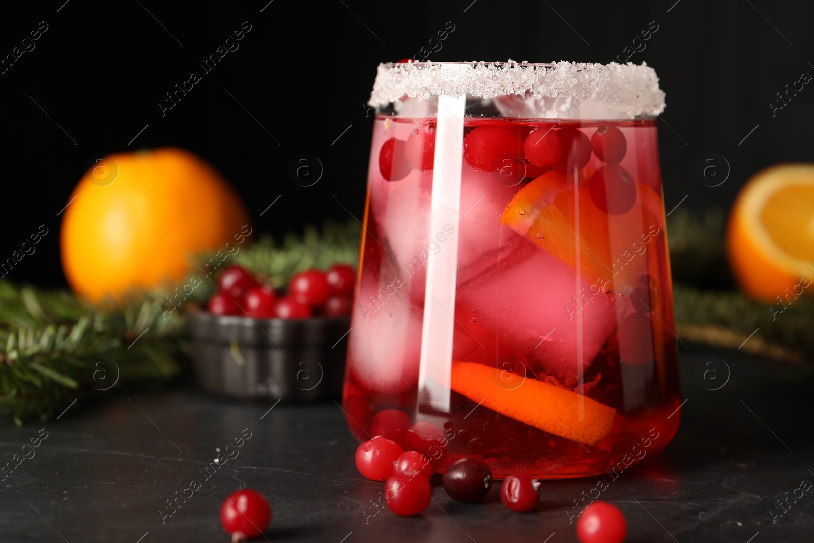 Photo of Tasty cranberry cocktail with ice cubes in glass on dark gray table