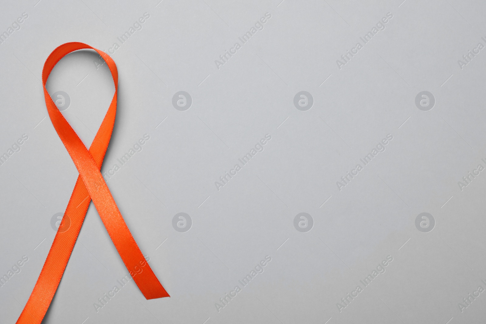 Photo of Orange ribbon on light grey background, top view with space for text. Multiple sclerosis awareness