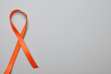 Photo of Orange ribbon on light grey background, top view with space for text. Multiple sclerosis awareness