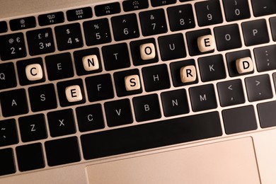 Photo of Wooden cubes with word Censored on laptop keyboard, flat lay