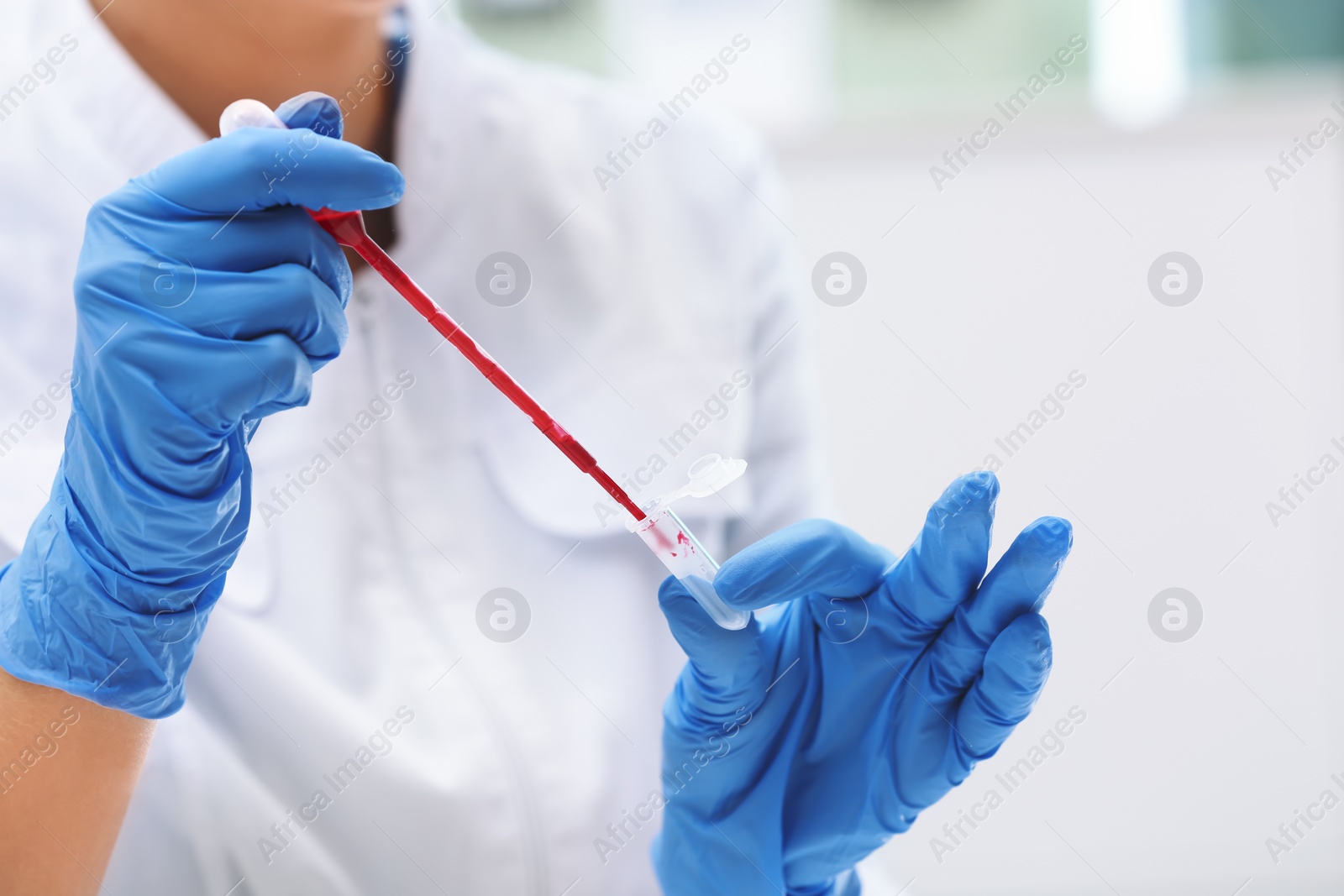 Photo of Scientist dripping blood into test tube in laboratory