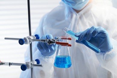 Photo of Scientist working with beaker and test tube in laboratory, closeup