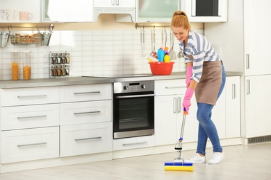 Woman cleaning floor with mop in kitchen