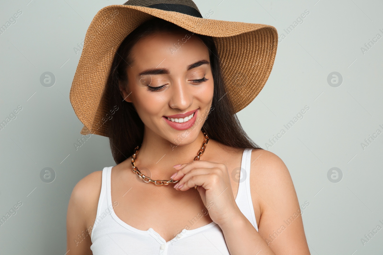 Photo of Beautiful young woman wearing straw hat on light grey background. Stylish headdress