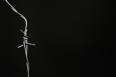 Photo of Metal barbed wire on black background. Space for text