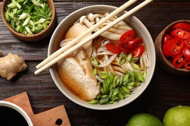 Delicious ramen with meat and ingredients on wooden table, flat lay. Noodle soup