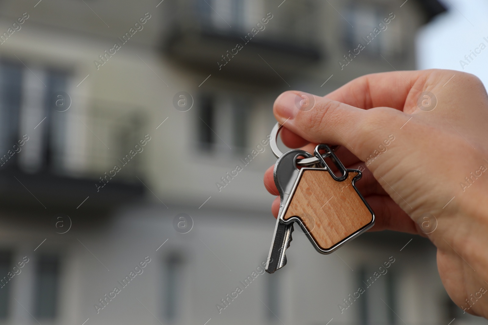 Photo of Woman holding house keys outdoors, closeup with space for text. Real estate agent