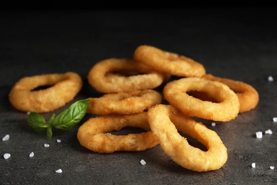 Photo of Fried onion rings and basil leaves on grey table