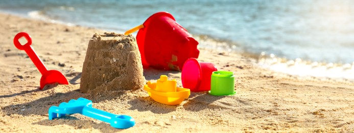 Set of plastic beach toys on sand near sea. Banner design