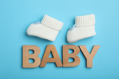 Photo of Flat lay composition with child's booties and word Baby on blue background
