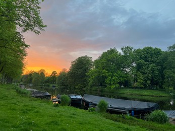 Scenic view of canal with moored boats at sunset