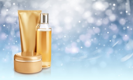 Image of Different cosmetic products on blue background with blurred snowflakes, space for text. Winter skin care