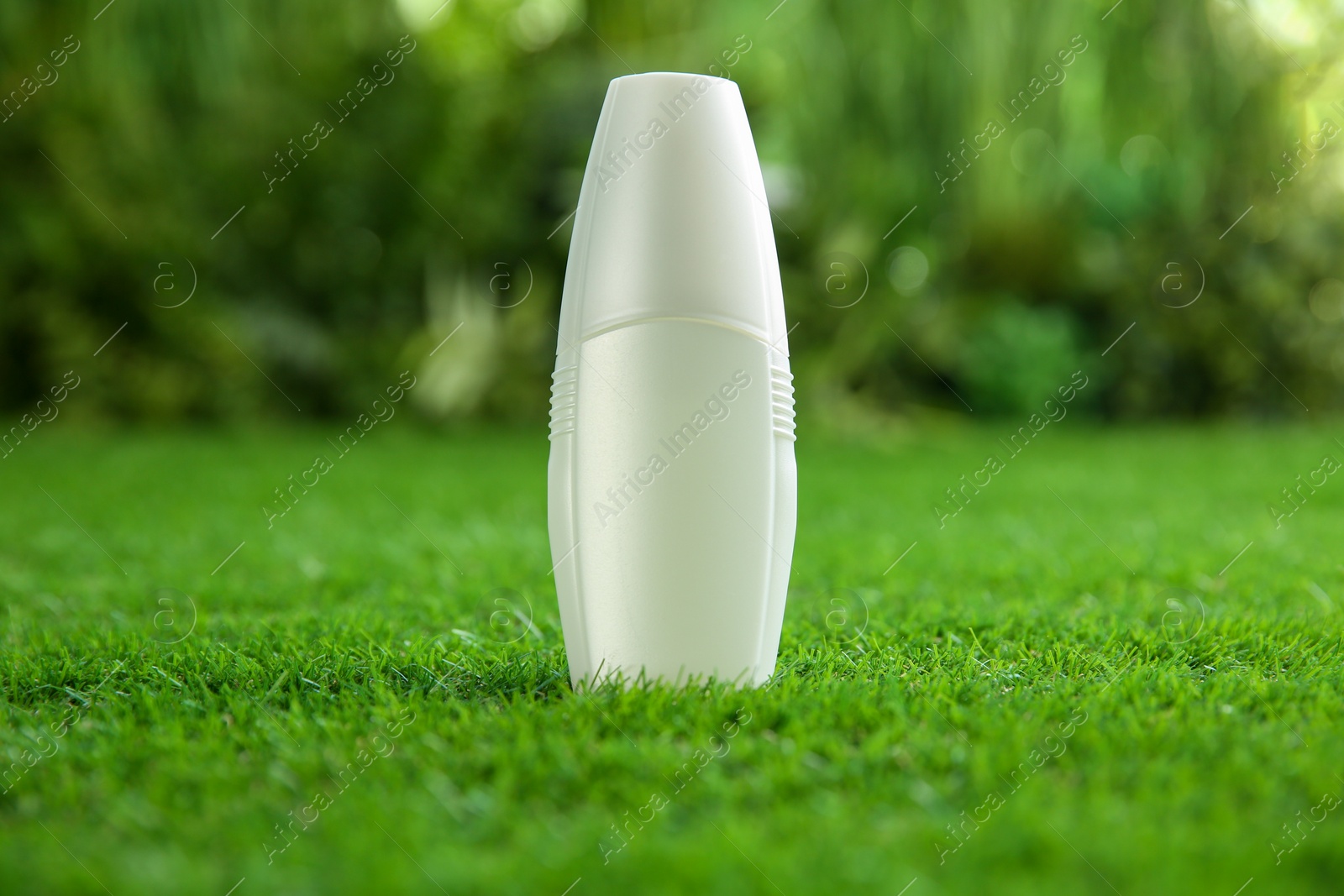 Photo of Bottle of insect repellent spray on green grass. Space for text