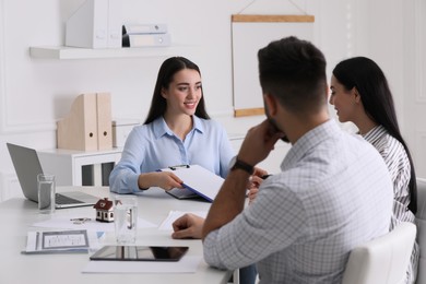 Photo of Happy young couple signing purchase contract in real estate agent's office. Mortgage concept