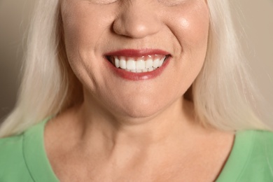 Photo of Smiling woman with perfect teeth on color background, closeup