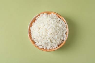 Bowl of tasty cooked rice on color background, top view