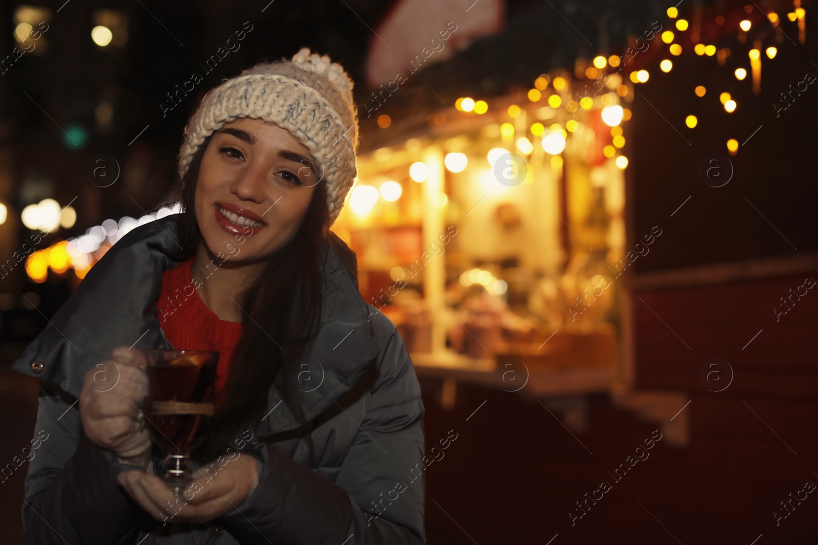 Photo of Woman with glass cup of mulled wine at winter fair. Space for text