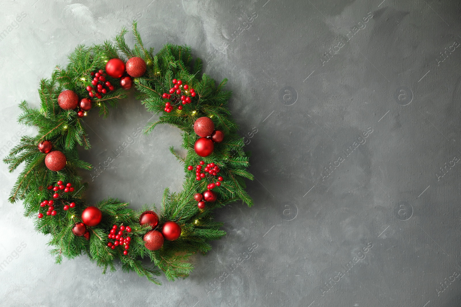 Photo of Beautiful Christmas wreath with festive decor on grey wall, space for text