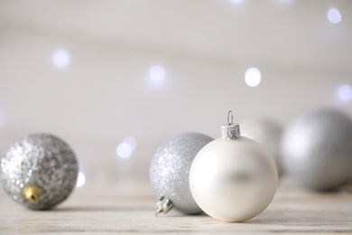 Beautiful Christmas balls on table against blurred festive lights. Space for text