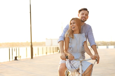 Happy couple riding bicycle outdoors on summer day