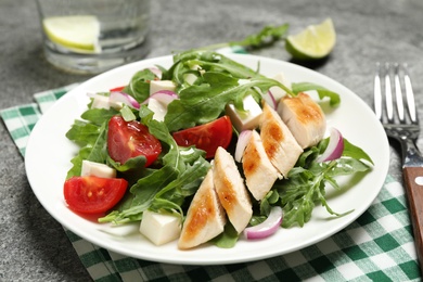 Delicious salad with meat, arugula and vegetables on grey table, closeup