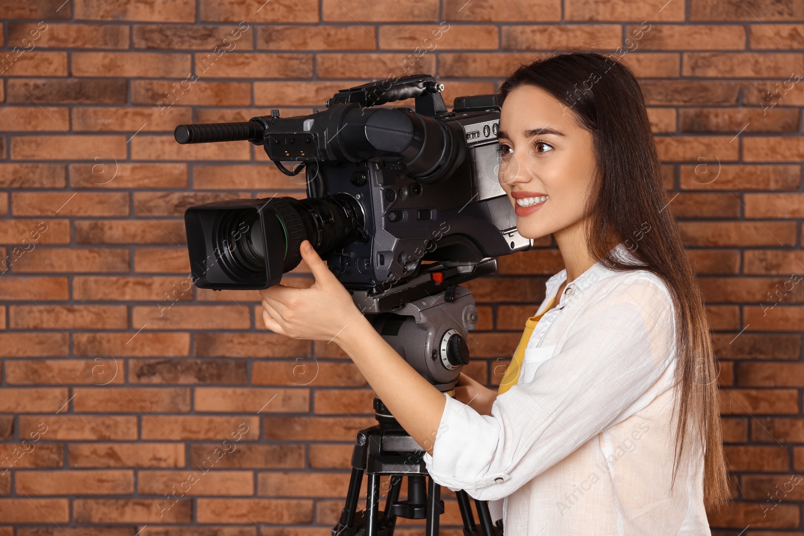 Photo of Operator with professional video camera near brick wall