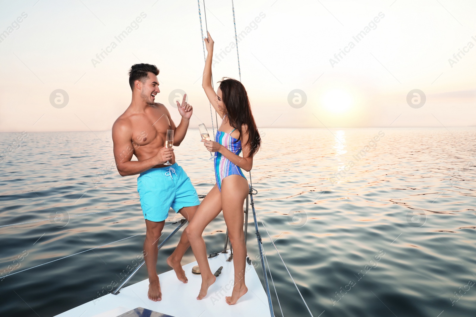 Photo of Young man and his girlfriend in bikini drinking champagne on yacht