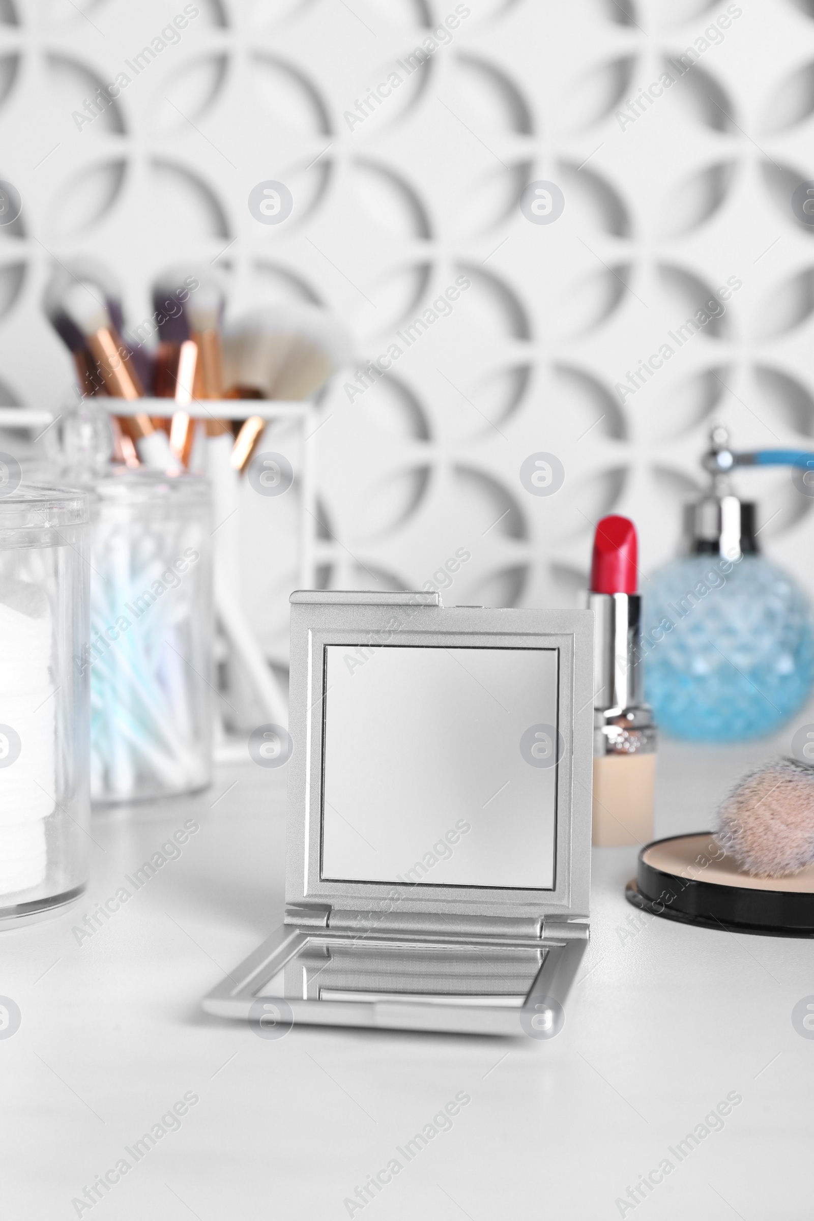 Photo of Stylish pocket mirror and cosmetic products on white table