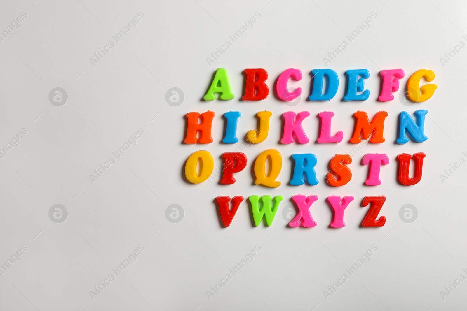 Photo of Colorful magnetic letters on white background, flat lay. Alphabetical order