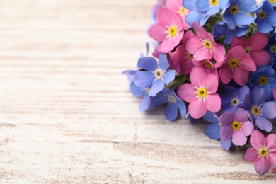 Photo of Beautiful Forget-me-not flowers on white wooden table. Space for text