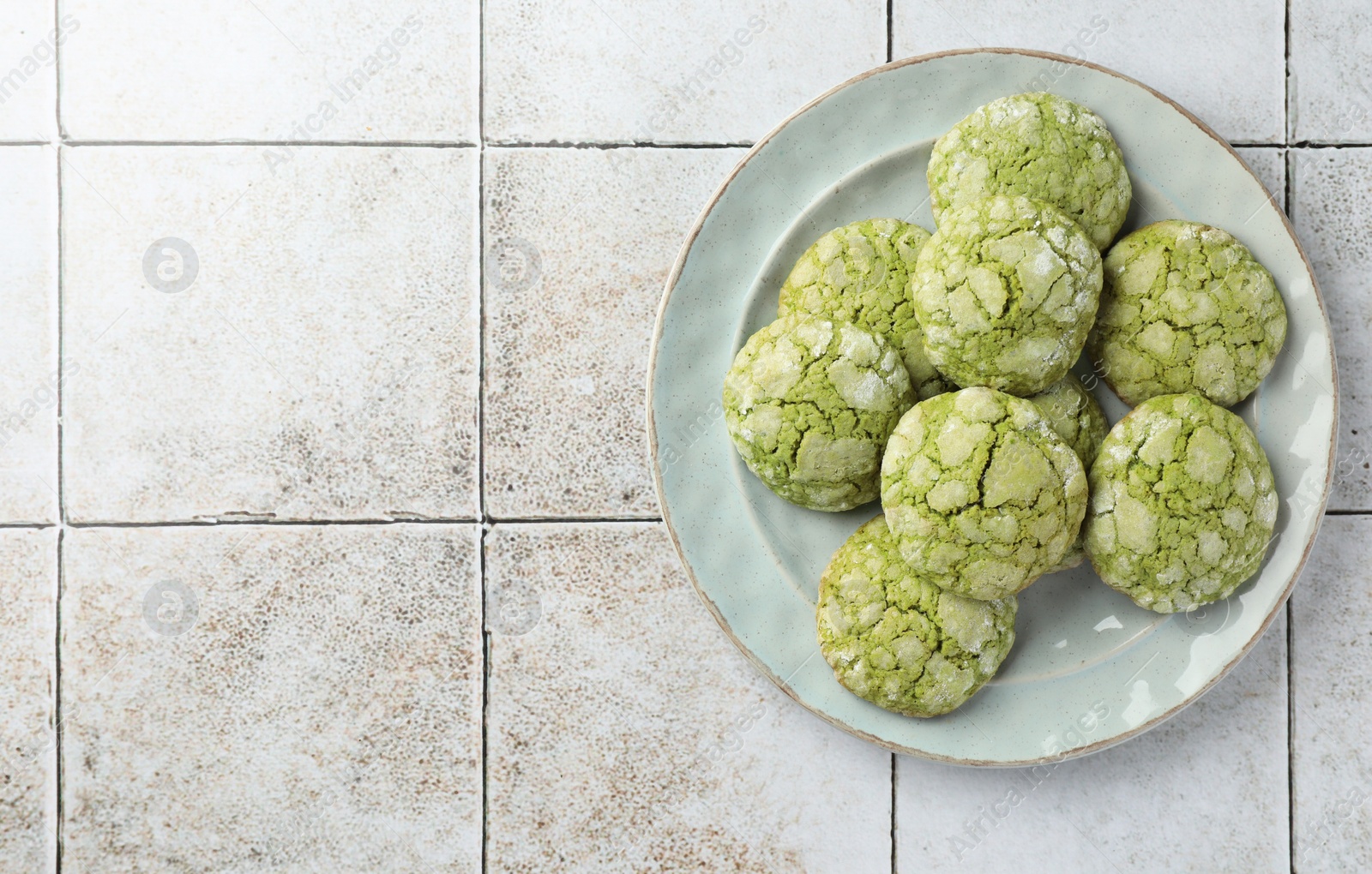 Photo of Plate with tasty matcha cookies on tiled table, top view. Space for text