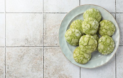 Plate with tasty matcha cookies on tiled table, top view. Space for text