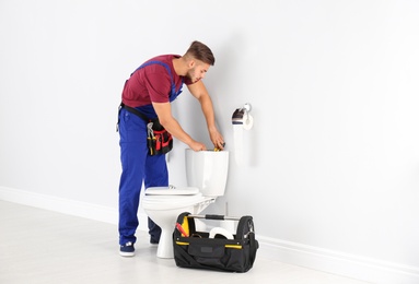 Young man working with toilet tank in bathroom