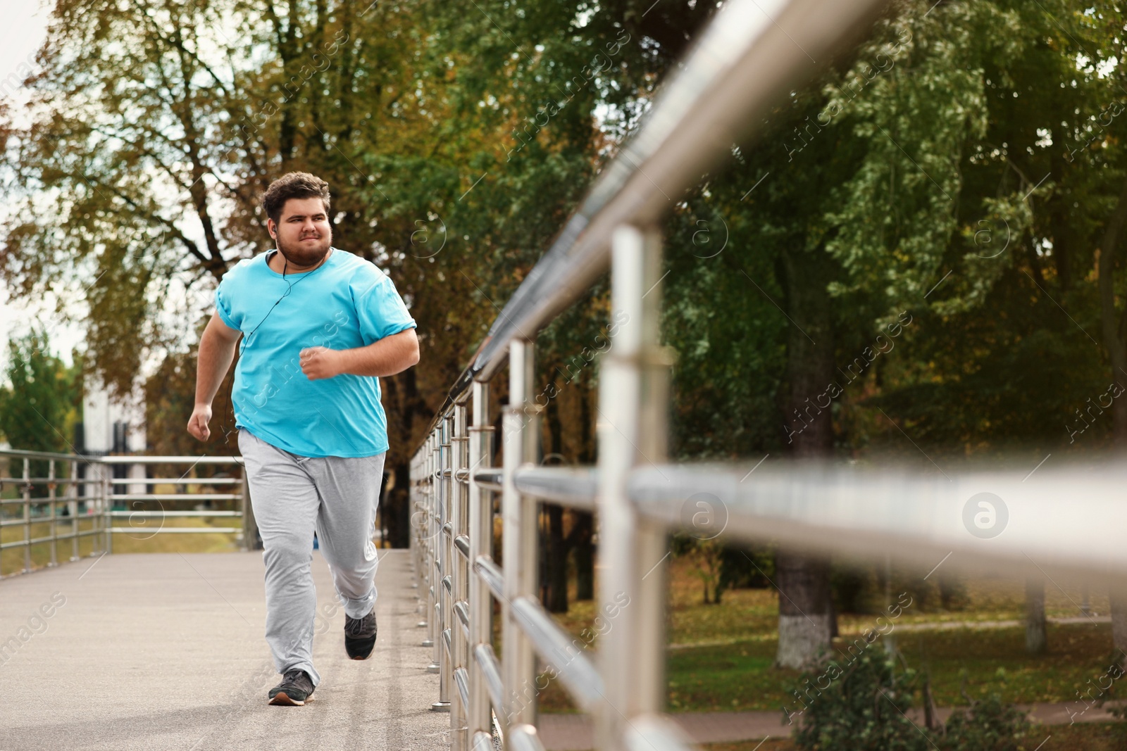 Photo of Young overweight man running outdoors. Fitness lifestyle