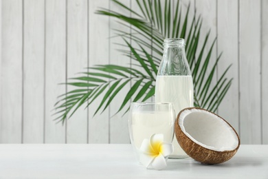 Composition with bottle and glass of coconut water on white wooden table