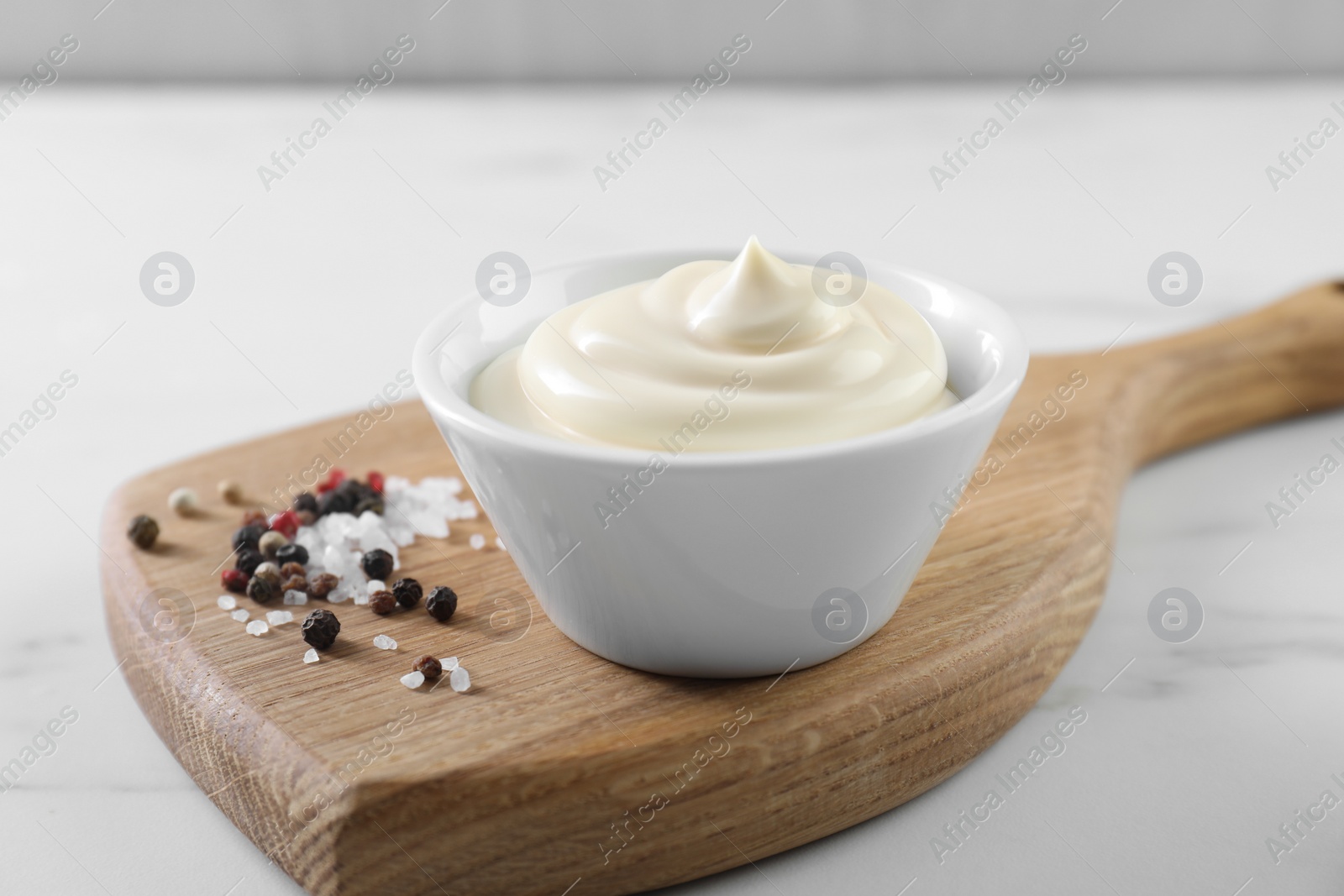 Photo of Tasty mayonnaise sauce in bowl and spices on white table, closeup