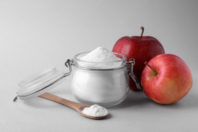 Photo of Jar, spoon with sweet fructose powder and ripe apples on white background