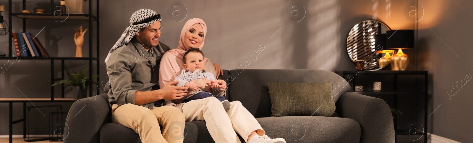 Image of Happy Muslim family with little son in living room. Banner design 