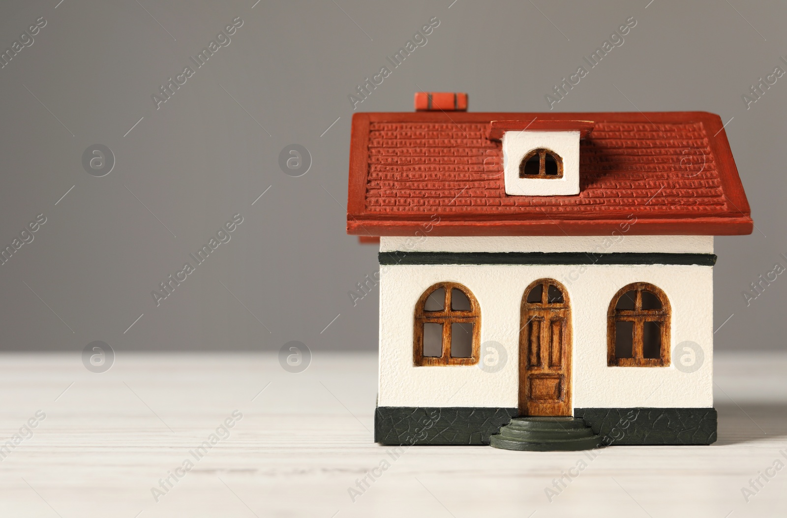 Photo of Mortgage concept. House model on white wooden table against grey background, space for text