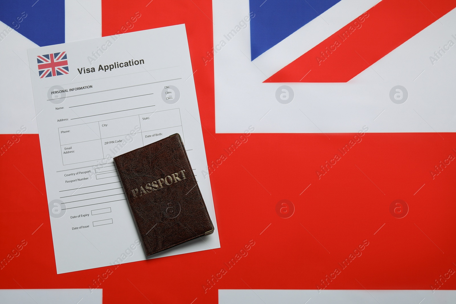 Photo of Immigration to United Kingdom. Visa application form and passport on flag, top view. Space for text