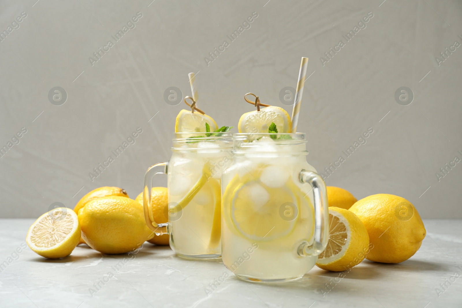 Photo of Natural lemonade with mint and fresh fruits on light grey marble table. Summer refreshing drink