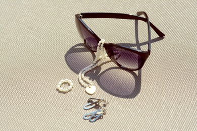 Photo of Stylish sunglasses and jewelry on grey surface