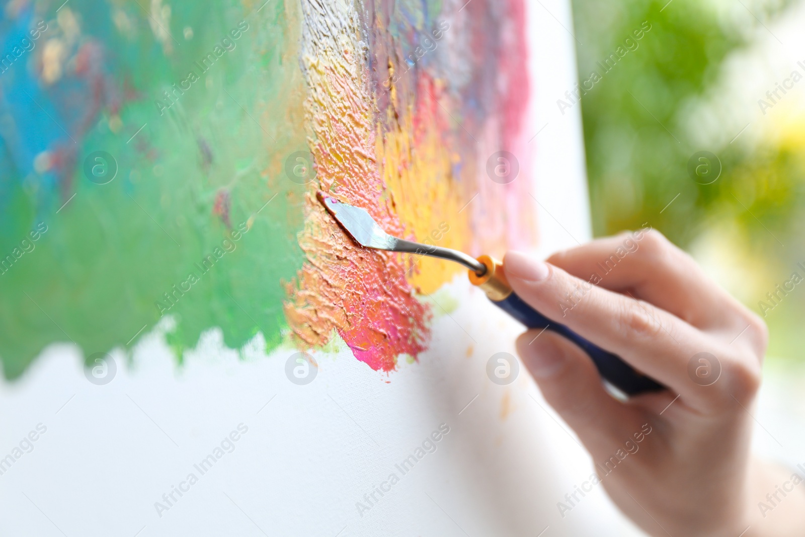 Photo of Artist painting on canvas with spatula, closeup