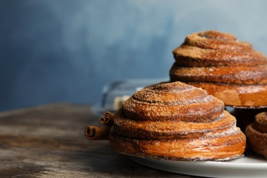 Plate with baked cinnamon rolls on wooden table, closeup. Space for text