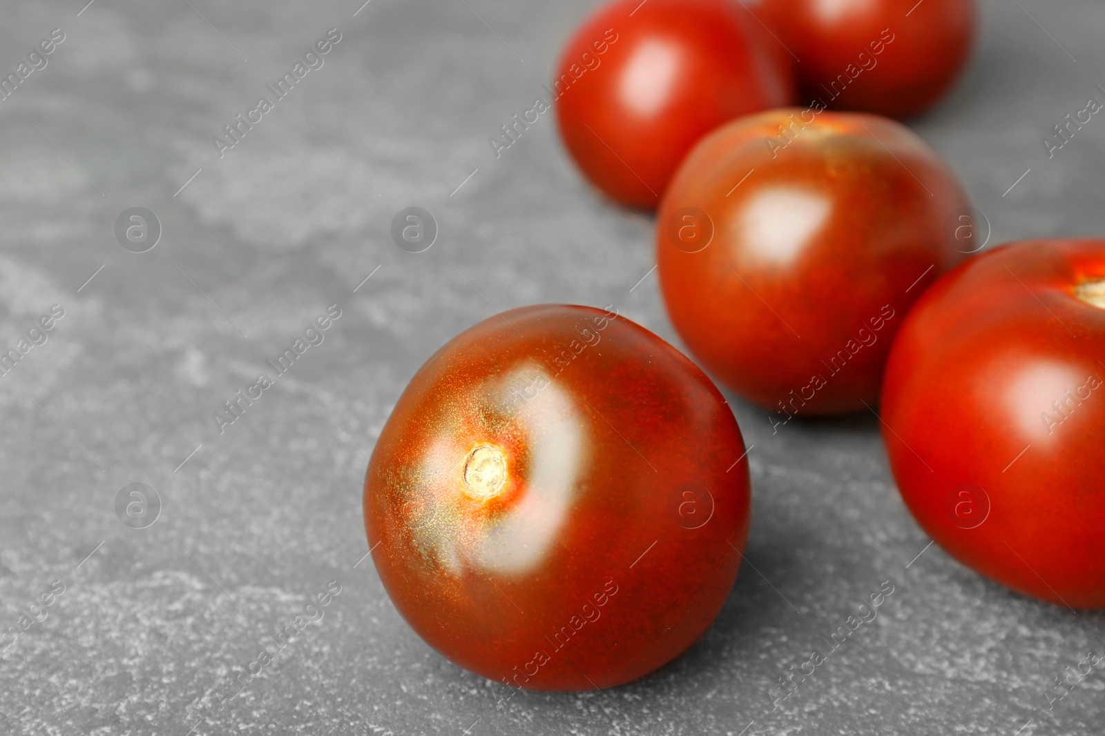 Photo of Fresh ripe brown tomatoes on grey table, closeup