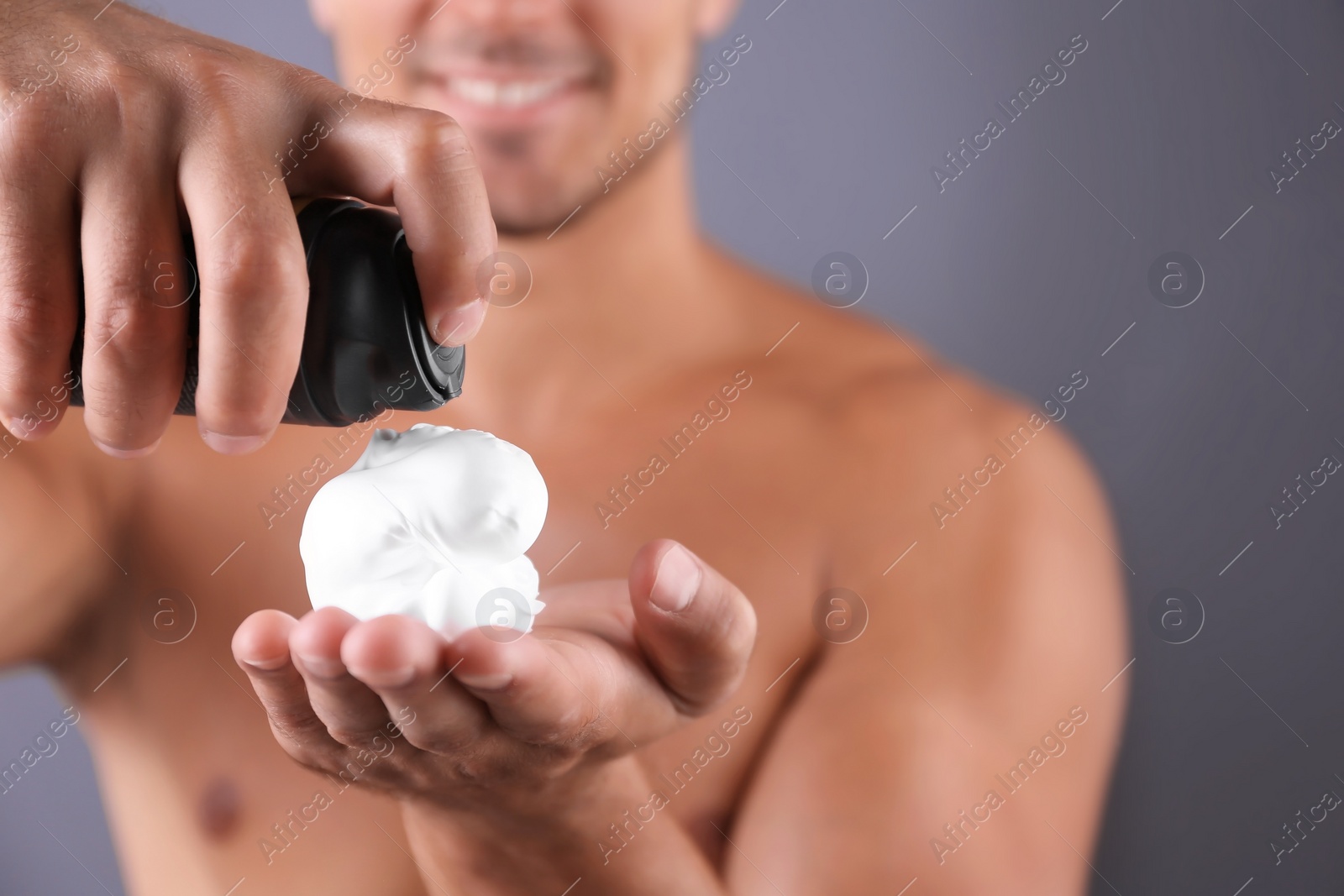 Photo of Young man with shaving foam against color background, closeup