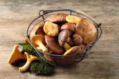 Photo of Basket with different wild mushrooms on wooden table
